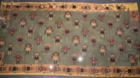 Mantle decorated with motifs of mythical warriors holding trophy heads